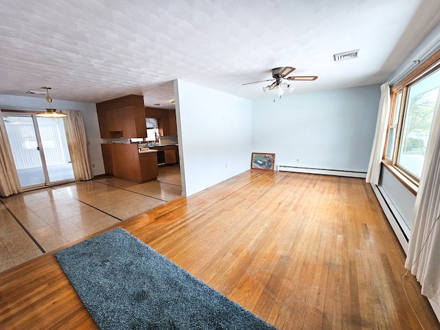 unfurnished living room with a baseboard radiator, plenty of natural light, and ceiling fan