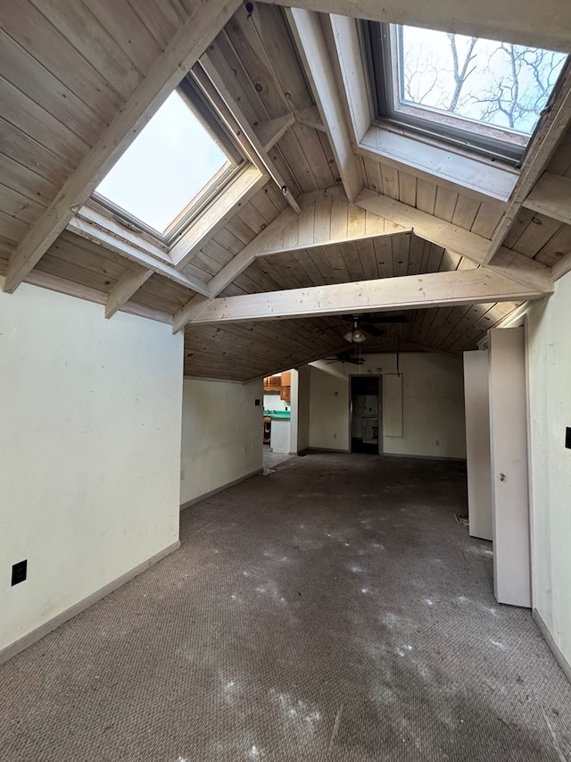 interior space featuring vaulted ceiling with skylight, wood ceiling, and baseboards