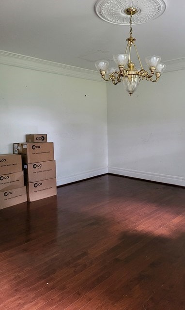 spare room with dark hardwood / wood-style flooring, crown molding, and a chandelier