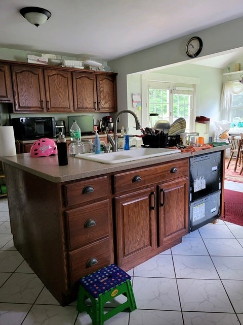 kitchen with sink, an island with sink, and black appliances