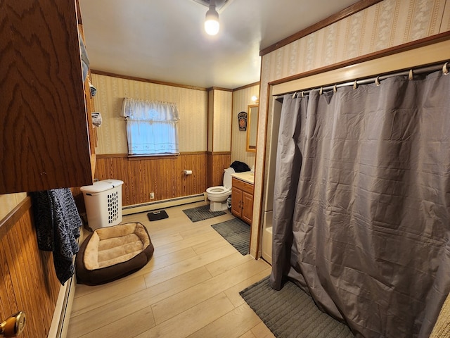 bathroom with toilet, wood-type flooring, ornamental molding, vanity, and a baseboard heating unit