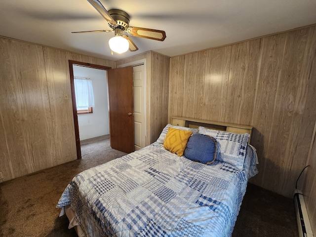 bedroom featuring dark colored carpet, a baseboard radiator, ceiling fan, and wood walls