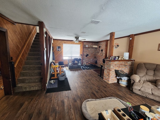 living room featuring ceiling fan, dark wood-type flooring, a textured ceiling, and wood walls