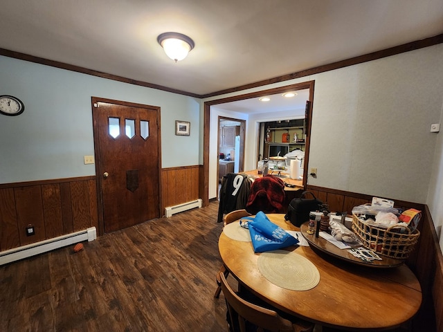 dining area featuring baseboard heating, ornamental molding, wooden walls, and hardwood / wood-style floors