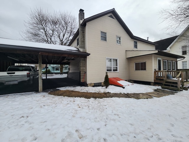 snow covered property with a wooden deck and a carport