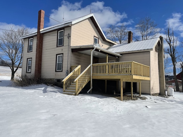 snow covered back of property with a wooden deck