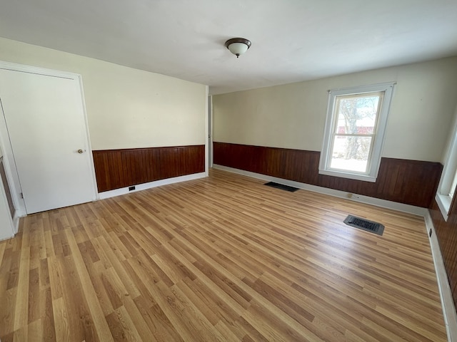 unfurnished room featuring light hardwood / wood-style flooring and wooden walls