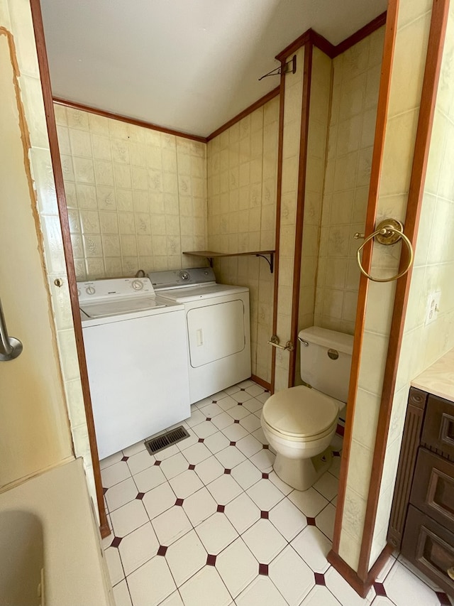 bathroom featuring crown molding, tile walls, separate washer and dryer, a tub, and toilet