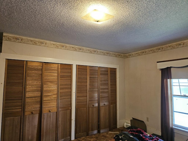 unfurnished bedroom with carpet, a textured ceiling, and two closets