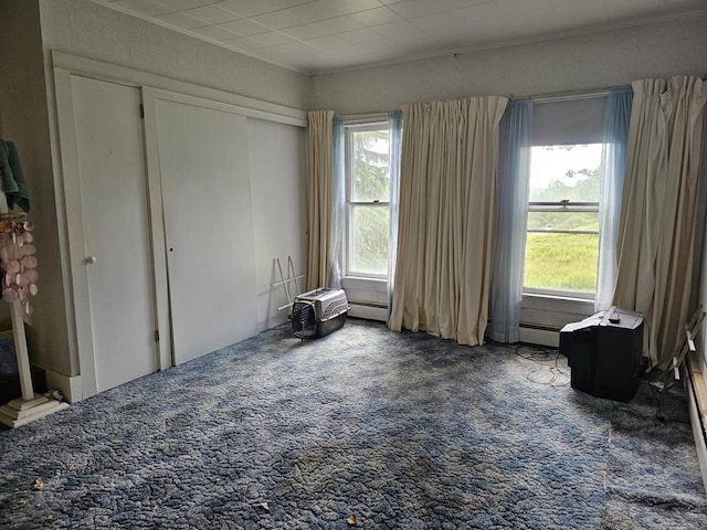 bedroom with dark carpet, a baseboard radiator, and a closet