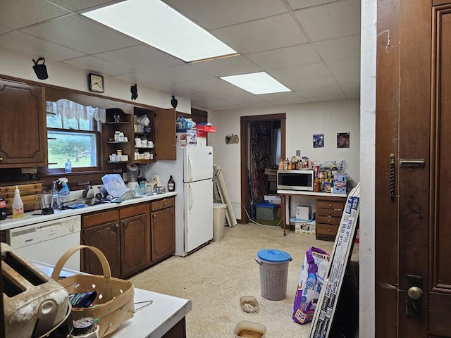 kitchen with dark brown cabinetry, a drop ceiling, and white appliances