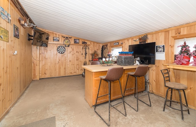 kitchen with wooden walls, vaulted ceiling, concrete flooring, a peninsula, and light countertops