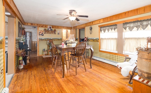 dining space featuring a baseboard heating unit, a ceiling fan, and wood finished floors