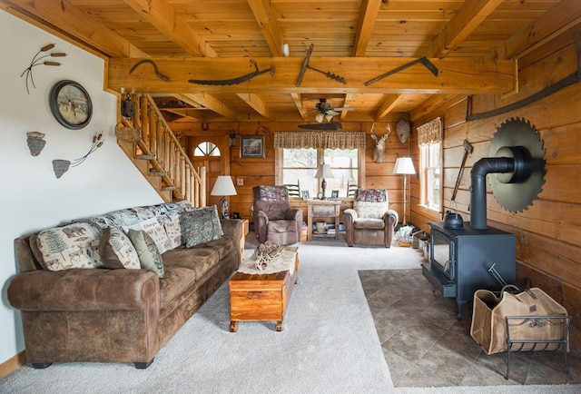 436 Teeter Rd, Genesee, PA 16923 - living room with wood walls, a wood stove, a wooden ceiling with exposed beams, a ceiling fan, and stairway
