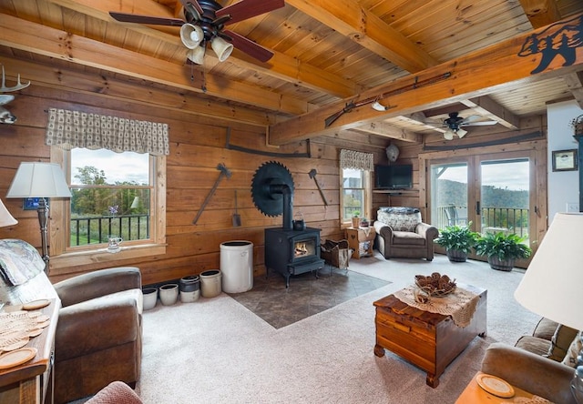 436 Teeter Rd, Genesee, PA 16923 - carpeted living room with a ceiling fan, a wood ceiling with exposed beams, a wood stove, and wooden walls