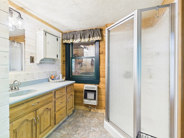 full bathroom featuring heating unit, a stall shower, wood walls, and vanity