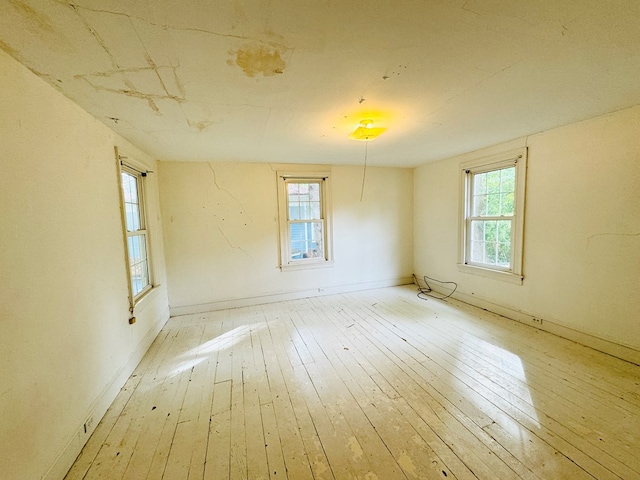 empty room with a wealth of natural light and light hardwood / wood-style floors