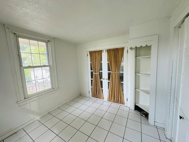 tiled spare room featuring a textured ceiling