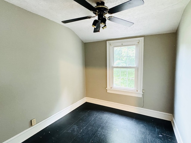 spare room with a textured ceiling, vaulted ceiling, and ceiling fan