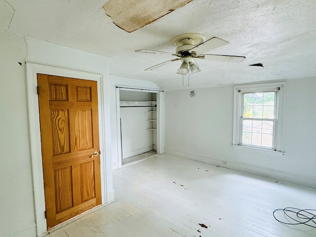 unfurnished bedroom with a textured ceiling, a closet, ceiling fan, and lofted ceiling