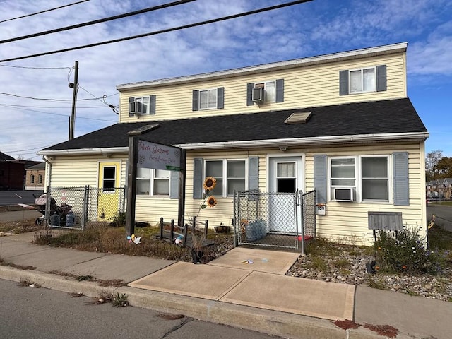 view of front of house featuring a gate, fence, and a wall mounted AC