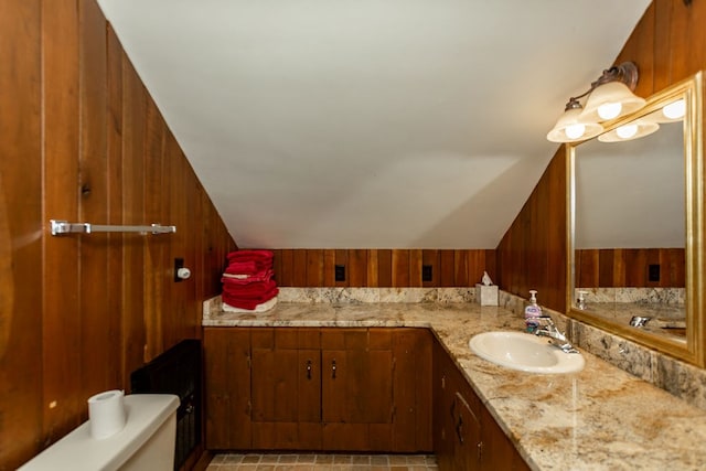 bathroom with vaulted ceiling and wooden walls