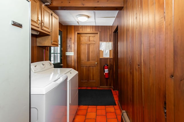 laundry room with cabinet space, baseboard heating, washer and dryer, and wood walls