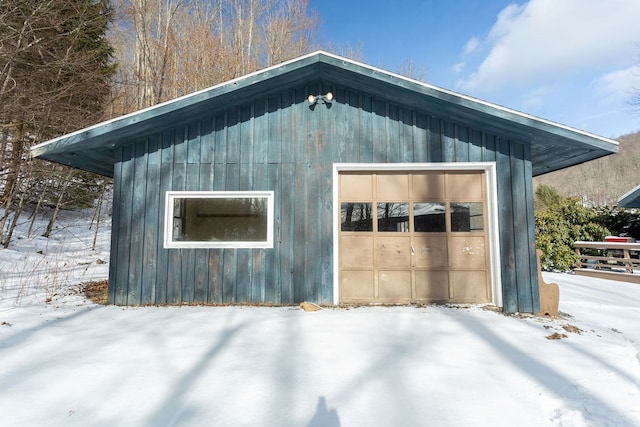 snow covered structure with an outbuilding