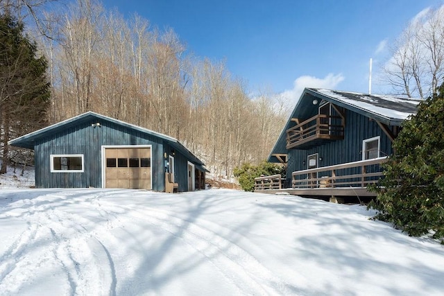 snow covered property featuring an outbuilding and a garage