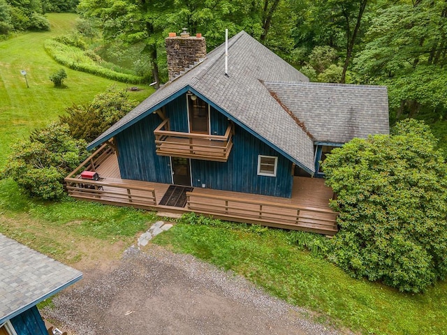 view of front of property with a front yard, a chimney, and a shingled roof