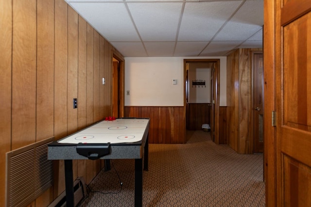 game room with a paneled ceiling, a baseboard radiator, carpet floors, and wood walls