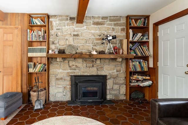 living area featuring beam ceiling, wooden walls, and built in shelves