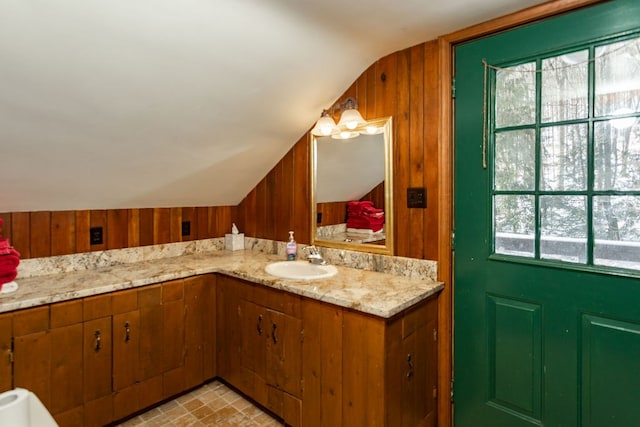 bathroom featuring sink, wooden walls, and vaulted ceiling