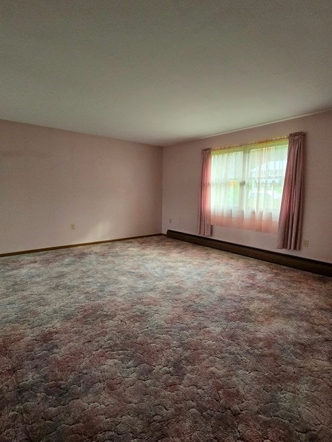 empty room with carpet flooring and a baseboard radiator