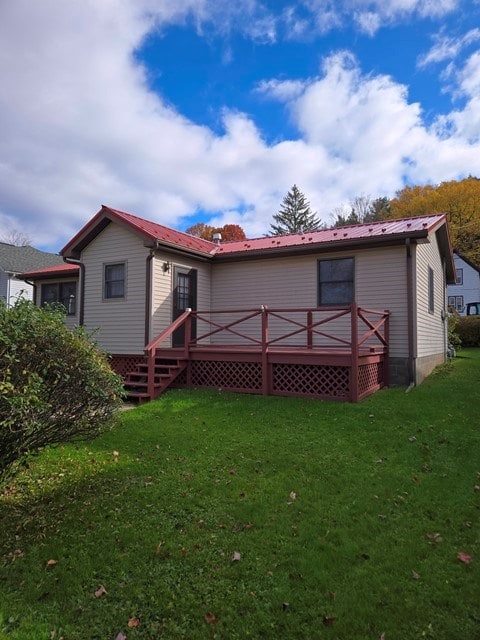 rear view of house featuring a deck and a lawn