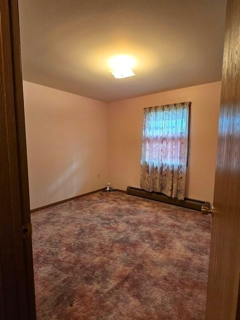 carpeted spare room featuring a baseboard radiator