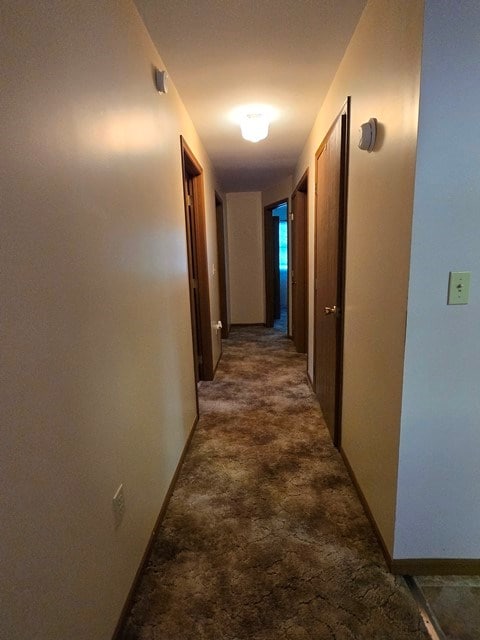 hall featuring dark colored carpet