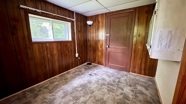 128 Bradford St, Sayre, PA 18840 - empty room featuring stone floors, wooden walls, baseboards, and a paneled ceiling