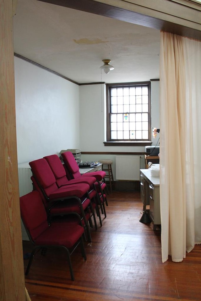 sitting room featuring radiator heating unit, crown molding, and wood-type flooring