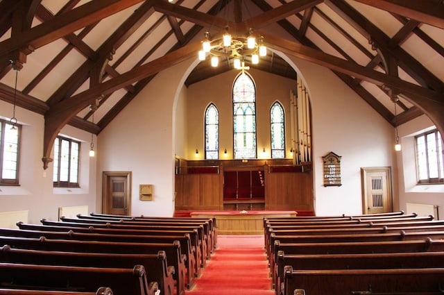 miscellaneous room with plenty of natural light, high vaulted ceiling, beamed ceiling, and an inviting chandelier