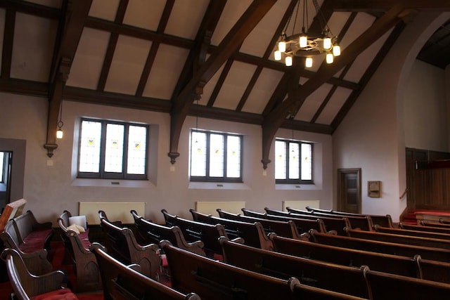 home theater featuring beamed ceiling, high vaulted ceiling, and an inviting chandelier