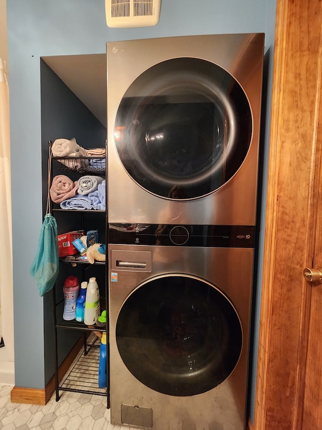 washroom featuring stacked washer / drying machine and light tile patterned flooring