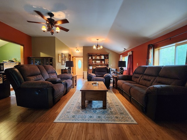 living room with lofted ceiling, wood-type flooring, and ceiling fan with notable chandelier