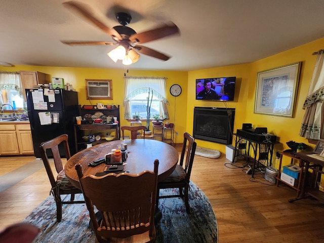 dining room with ceiling fan, light hardwood / wood-style flooring, a wall mounted air conditioner, and sink