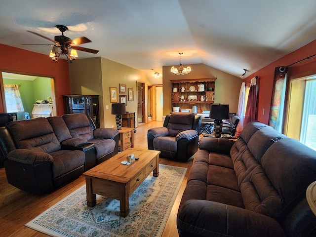 living room featuring hardwood / wood-style floors, ceiling fan with notable chandelier, a wealth of natural light, and vaulted ceiling