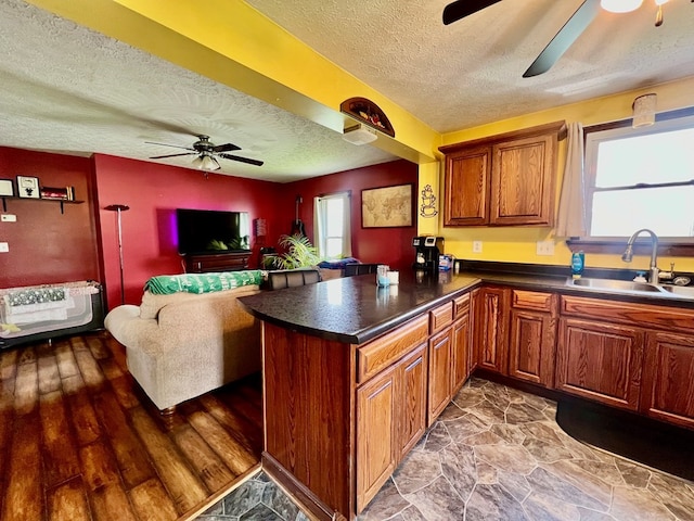 kitchen with sink, hardwood / wood-style flooring, a textured ceiling, kitchen peninsula, and heating unit