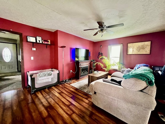 living room with a textured ceiling, ceiling fan, and dark wood-type flooring