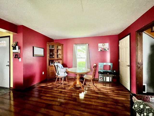 dining space with a textured ceiling and dark hardwood / wood-style floors