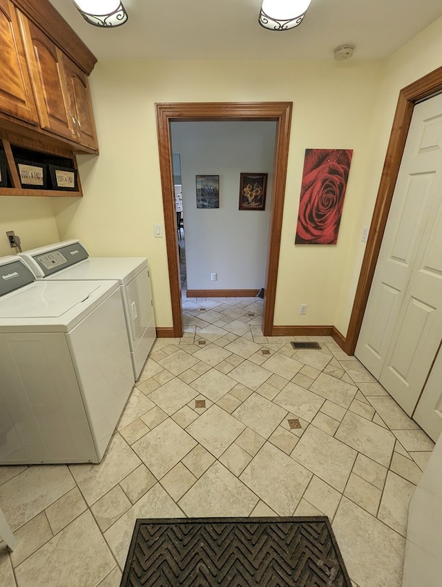 clothes washing area with separate washer and dryer and cabinets