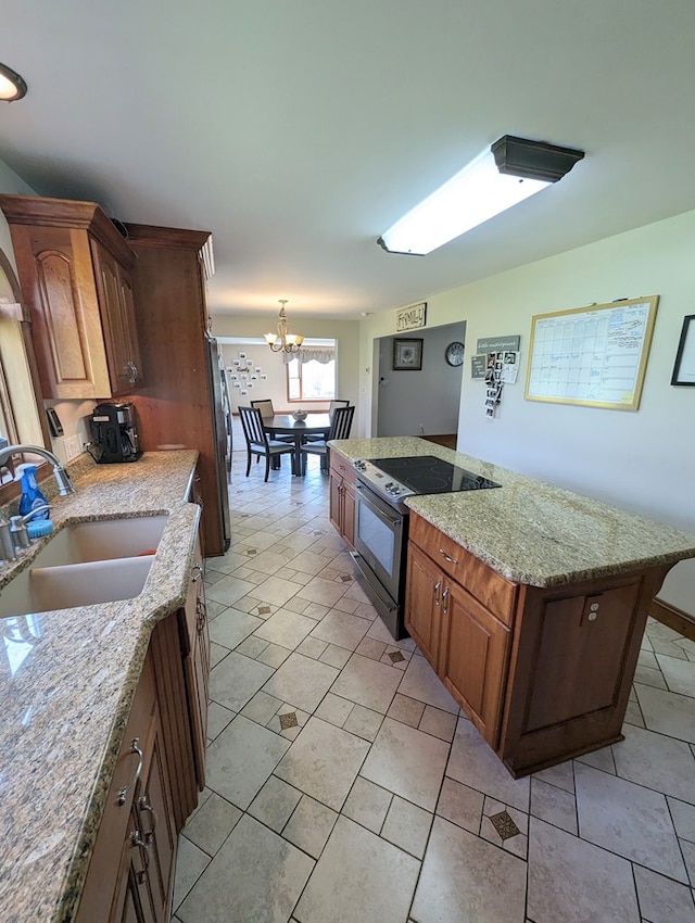 kitchen featuring stainless steel fridge, light stone counters, black range with electric cooktop, sink, and an inviting chandelier